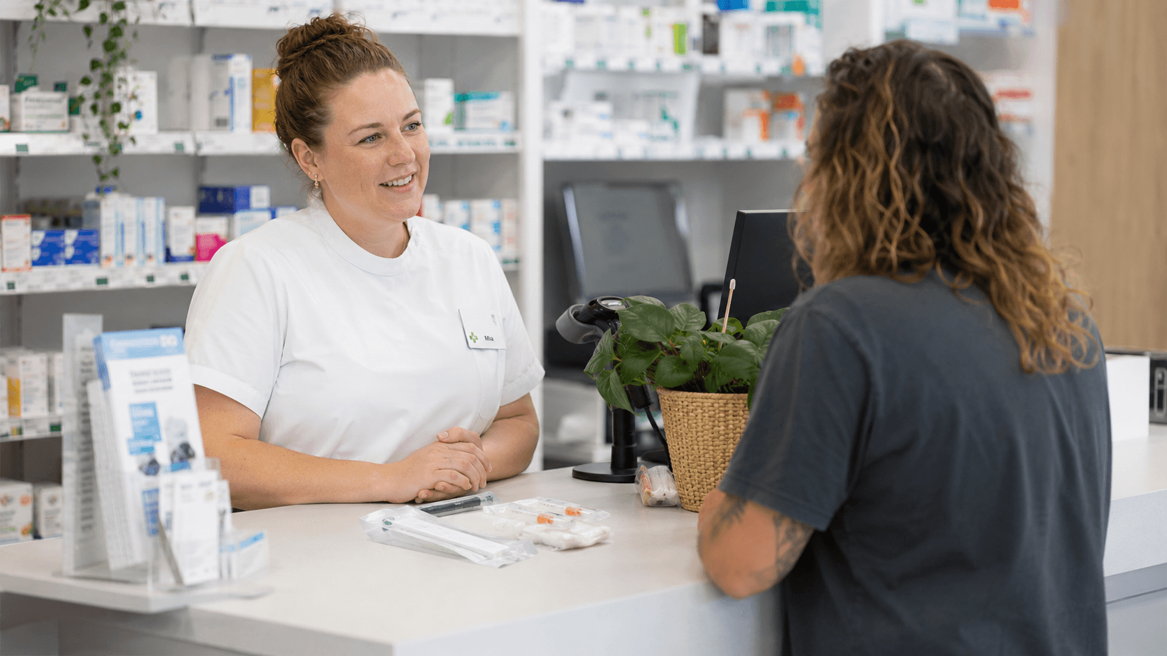 A pharmacist consulting with a customer about a needle and syringe kit at an Australian community pharmacy.
